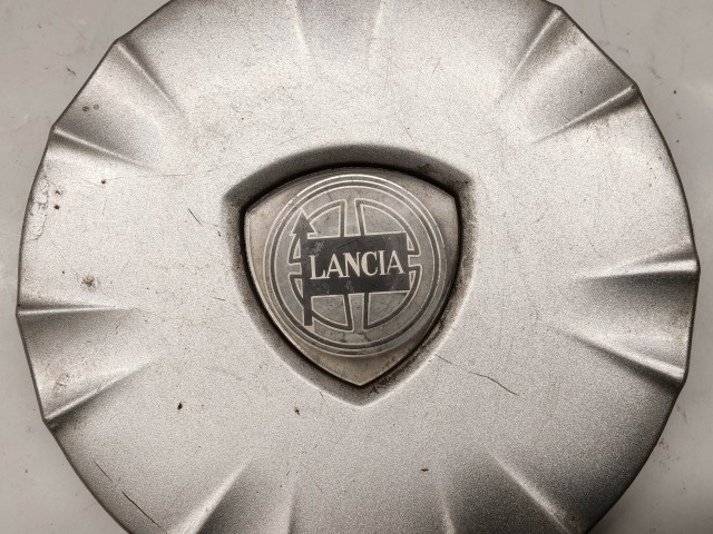 214300 Lancia Ypsilon II. 2003-2011 felni közép kupak, a képen látható állapotban, két rögzítő fül törött, egy hiányzik